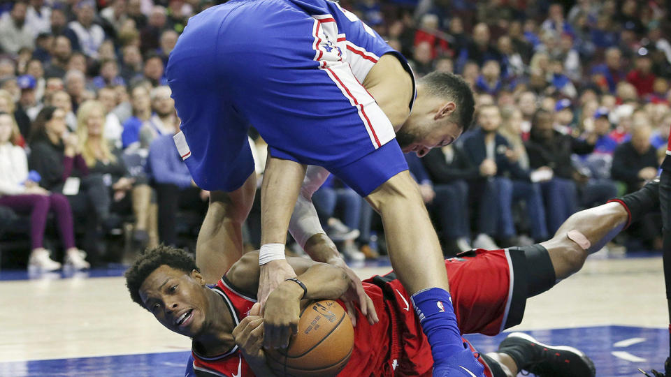 Toronto Raptors guard Kyle Lowry, bottom, and Philadelphia 76ers guard Ben Simmons vie for a loose ball. (AP Photo/Rich Schultz)