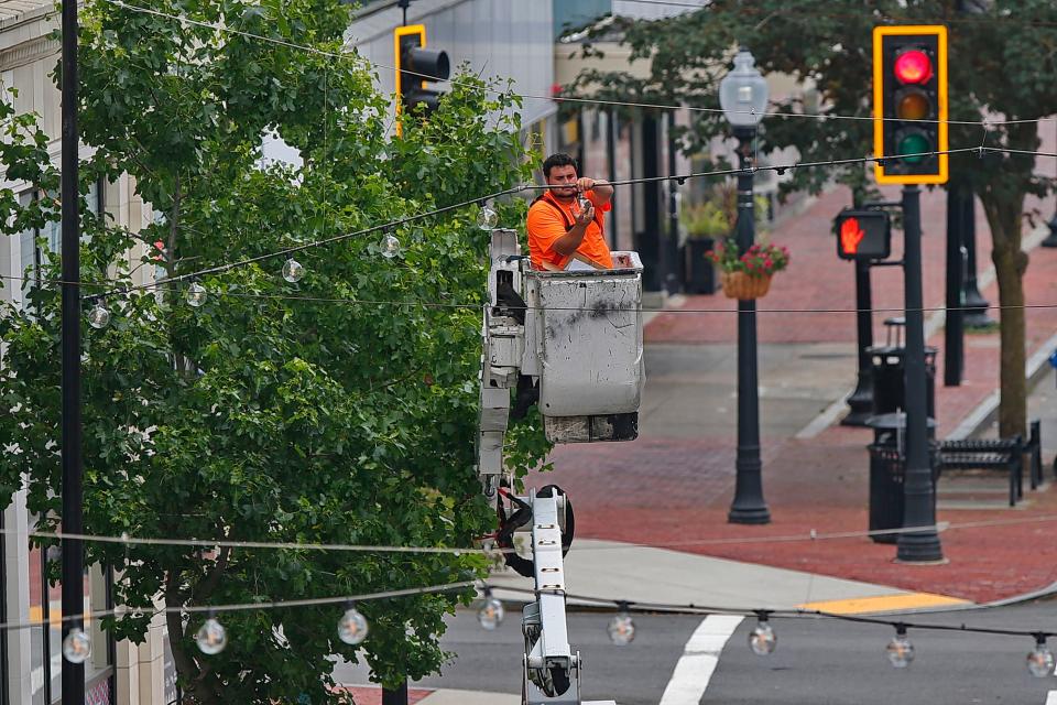 Kyle Vasquez installs lights on arches lining Purchase Street in downtown New Bedford. These lights will become a permanent addition to the downtown area.