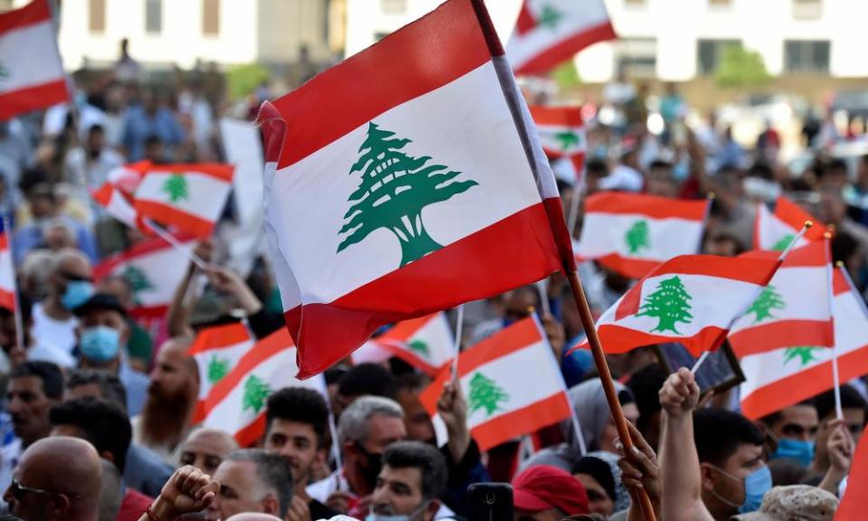 Anti-government protesters wave national flags during a protest in Beirut, demanding a transitional government as Lebanon grapples with its worst economic crisis in decades.