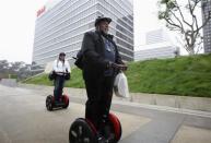 Apple co-founder Steve Wozniak carries the new iPad which he just purchased, as he and his wife Janet (L) ride their personal Segways to their hotel, after waiting in line overnight with customers to purchase the new iPad at the Apple Store in Century City Westfield Shopping Mall, Los Angeles, California March 16, 2012.