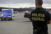 Federal police watch a container of vaccines against COVID-19 produced by Oxford/AstraZeneca arrive from India at the International airport in Sao Paulo, Brazil, Friday, Jan. 22, 2021. (AP Photo/Marcelo Chello)