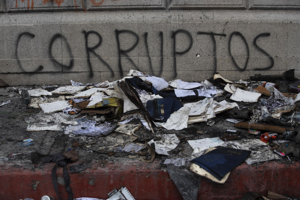 Debris lays in front of graffiti that reads in Spanish "Corrupt," outside of the Congress building that was damaged during protests in Guatemala City, Sunday, Nov. 22, 2020. Protesters broke into the building and set it partially on fire amid growing demonstrations against President Alejandro Giammattei and the legislature for approving a controversial budget that cut educational and health spending. (AP Photo/Moises Castillo)