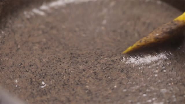 Stirring black sesame paste with spatula in a pot