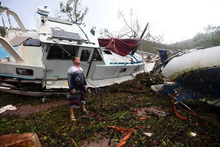 Local resident Bradley Mitchell inspects the damage to a relative's boat after it smashed against the bank after Cyclone Debbie passed athrough the township of Airlie Beach, located south of the northern Australian city of Townsville, March 29, 2017. AAP/Dan Peled/via REUTERS