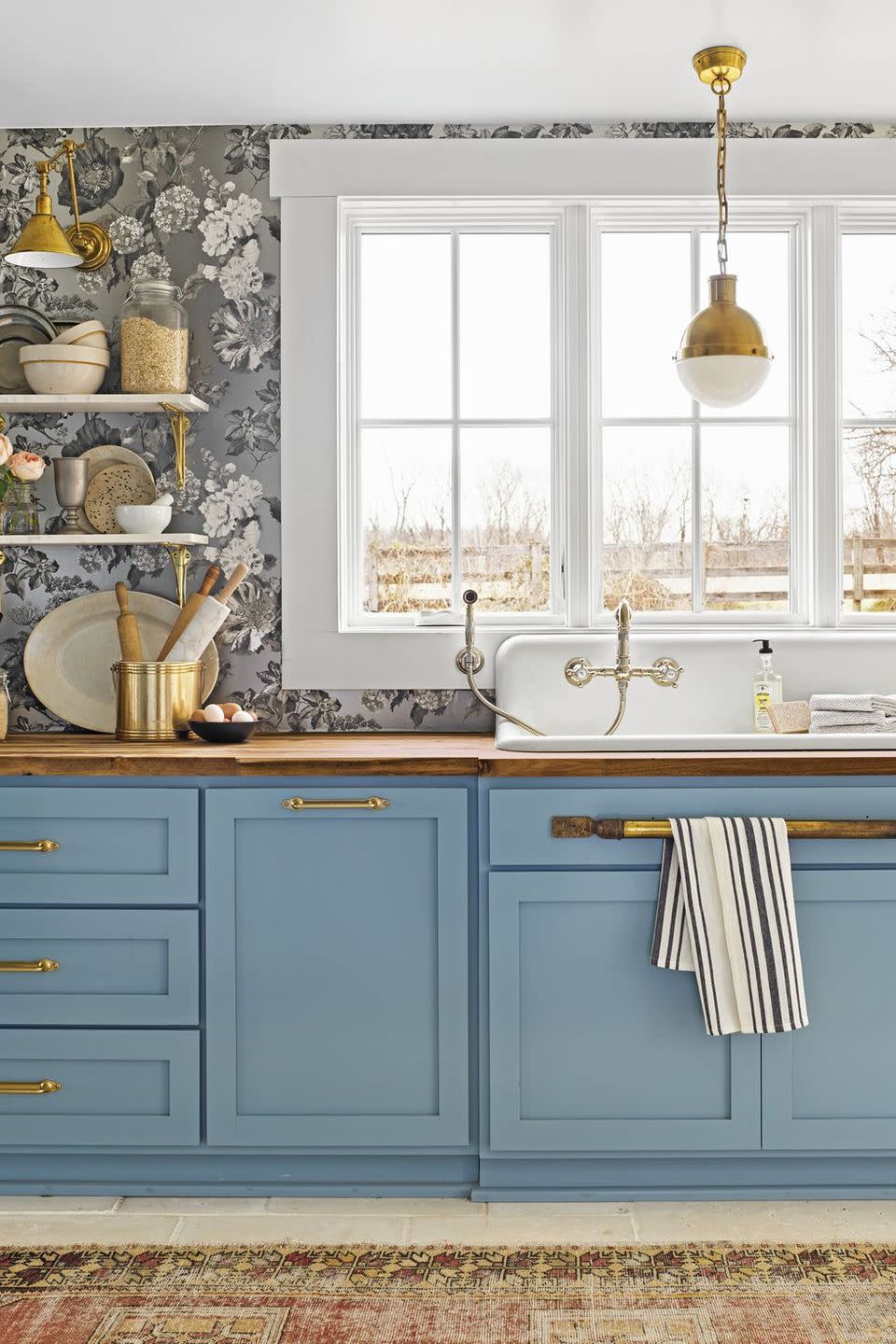 kitchen with blue painted cabinets paired with a silvery tone on tone floral wallpaper