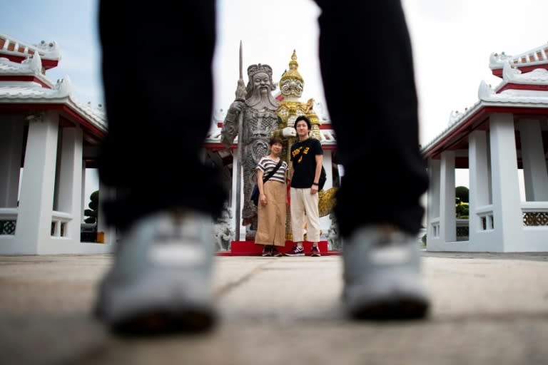 Tourists have their pictures taken with an art installation by Thai artist Komkrit Tepthian