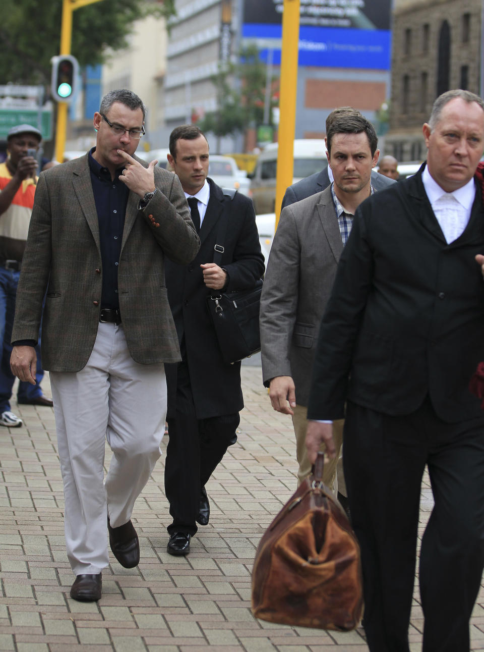 Oscar Pistorius, second from left, arrives at the high court in Pretoria, South Africa, Monday, March 10, 2014. The testimony in the first week of Pistorius' murder trial was jaw dropping at times, and more riveting evidence is expected as the prosecution seeks to prove beyond reasonable doubt that the double-amputee athlete intentionally shot dead his girlfriend Reeva Steenkamp, on Valentines Day in 2013. (AP Photo/Themba Hadebe)