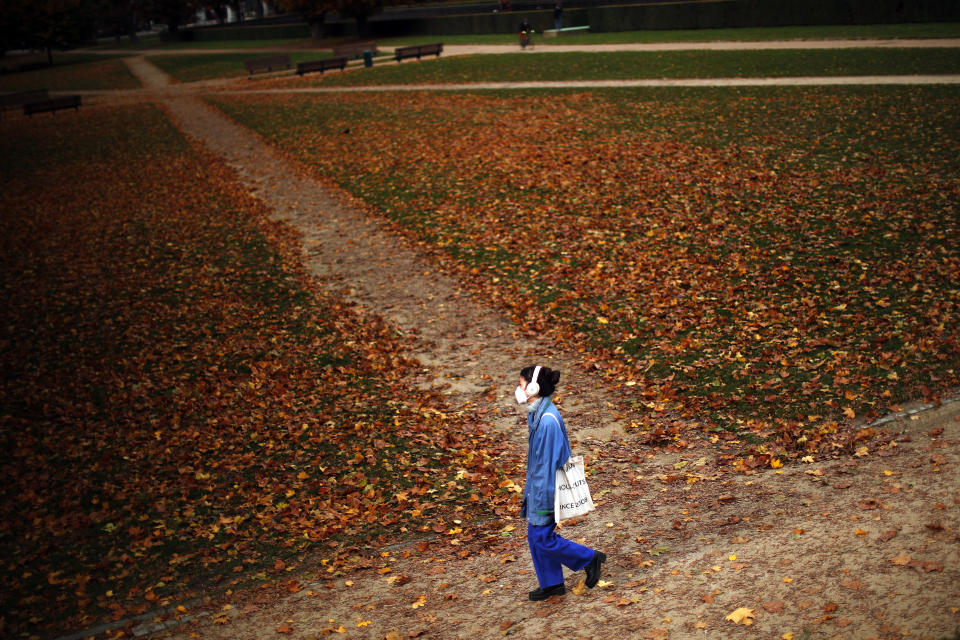 A woman, wearing a face mask to prevent the spread of the coronavirus COVID-19, walks along Cinquantenaire park in an autumn day in Brussels, Friday, Oct. 23, 2020. Belgian Prime Minister Alexander De Croo stopped short Friday of imposing another full lockdown, as the country did in March, but introduced a series of new restrictive measures as the number of COVID-19 related hospital admissions and deaths continue to soar. (AP Photo/Francisco Seco)