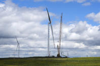 A wind turbine is under construction near a sunflowers farmland on the grassland in Zhangbei county, in north China's Hebei province on Aug. 15, 2022. The world's two biggest emitters of greenhouse gases are sparring on Twitter over climate policy, with China asking if the U.S. can deliver on the landmark climate legislation signed into law by President Joe Biden this week. (AP Photo/Andy Wong)