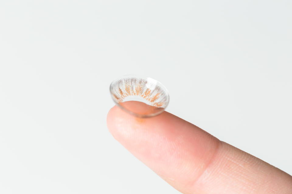 Finger with contact lens on blurred background.