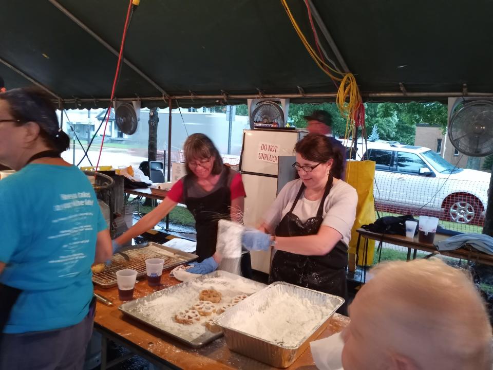 Volunteers work at the homemade waffle booth at the St. Joseph Festival in Dover. They deep-fry and put powered sugar on the waffles.