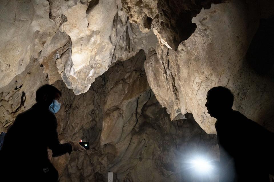 Visitors look inside the abandoned Wanling cave near Manhaguo village in southern China's Yunnan province on Wednesday, Dec. 2, 2020. Villagers said the cave had been used as a sacred altar presided over by a Buddhist monk _ precisely the kind of contact between bats and people that alarms scientists. (AP Photo/Ng Han Guan)