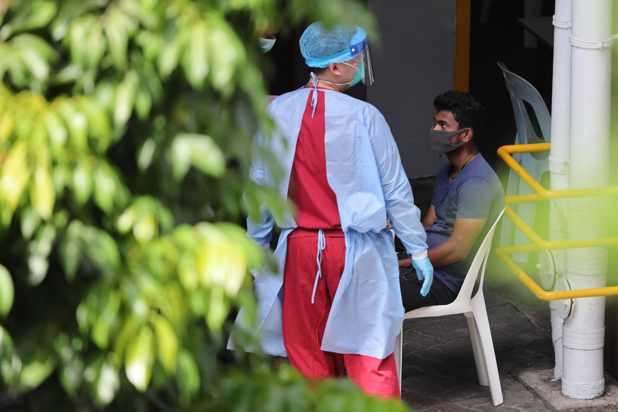 SINGAPORE - APRIL 29:  A healthcare worker wearing the personal protective equipment attends to a foreign worker at a dormitory on April 29, 2020 in Singapore. Singapore is now battling to control a huge outbreak in the coronavirus (COVID-19) local transmission cases among the migrant workers.  (Photo by Suhaimi Abdullah/Getty Images)