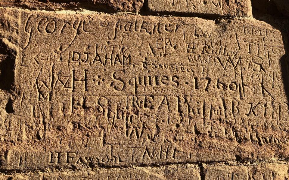 Graffiti from the 18th and 19th Century on the walls of Kenilworth Castle brilliantly lit in winter sunshine