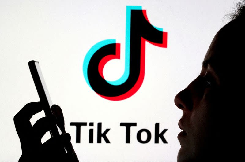 FILE PHOTO: A person holds a smartphone as TikTok logo is displayed behind in this picture illustration