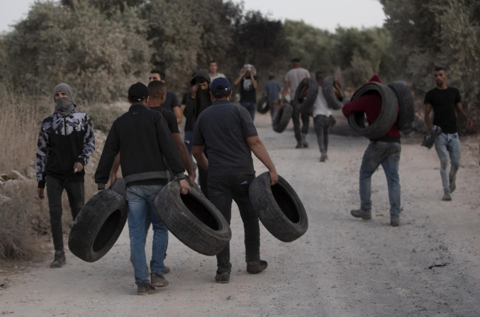 Palestinian demonstrators hold tires during a demonstration against the West Bank Jewish settlement outpost of Eviatar that was rapidly established last month, at the Palestinian village of Beita, near the West Bank city of Nablus, Sunday, June 27, 2021. The Palestinians say it was established on their farmland and fear it will grow and merge with other large settlements in the area. (AP Photo/Majdi Mohammed)