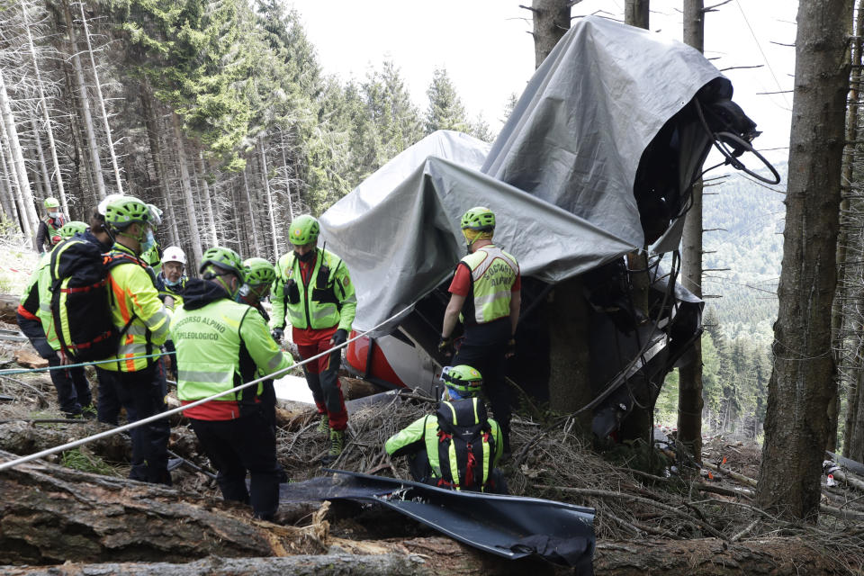 Rescuers search for evidence in the wreckage of a cable car after it collapsed near the summit of the Stresa-Mottarone line in the Piedmont region, northern Italy, Wednesday, May 26, 2021. Police have made three arrests in the cable car disaster that killed 14 people after an investigation showed a clamp, placed on the brake as a patchwork repair effort, prevented the brake from engaging after the lead cable snapped. (AP Photo/Luca Bruno)