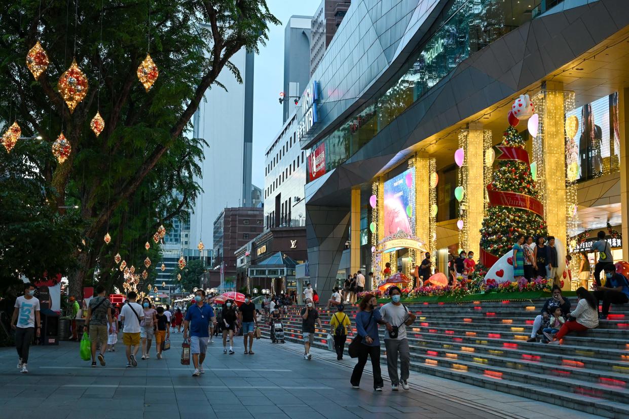 People walk past Christmas decorations at the Orchard road shopping district in Singapore on December 14, 2021. / AFP / Roslan RAHMAN