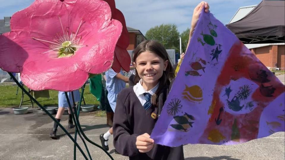 Rosie holding a flag, next to a giant flower