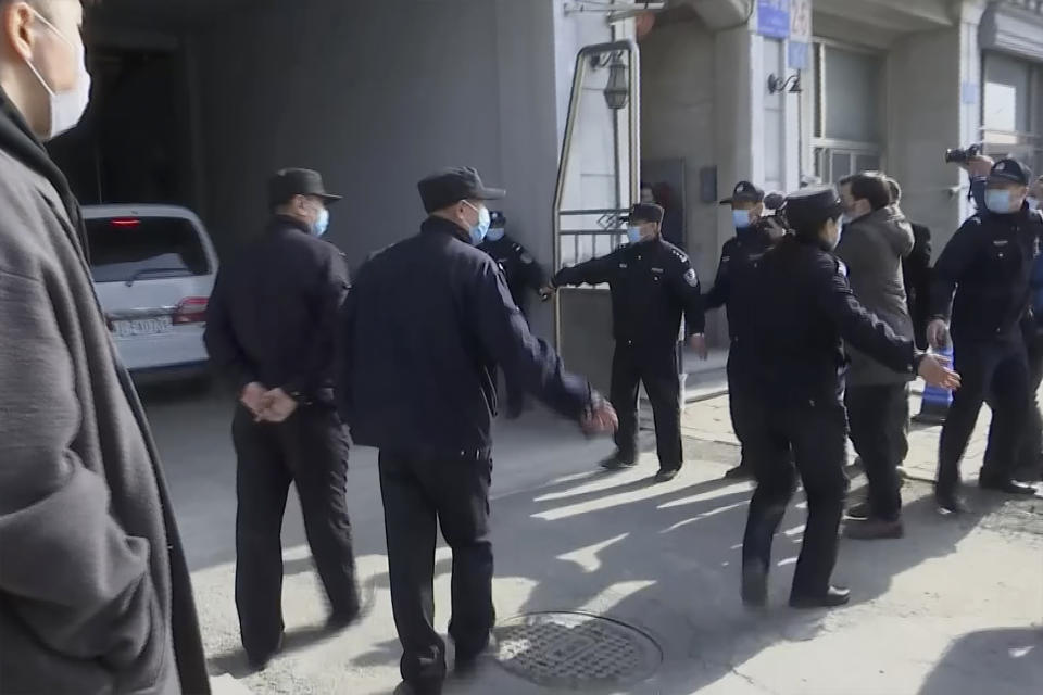 In this image taken from video, security officers stand guard as a police van, left, arrives at a court building in Dandong in northeastern China's Liaoning Province, Friday, March 19, 2021. China was expected to open the first trial Friday for Michael Spavor, one of two Canadians who have been held for more than two years in apparent retaliation for Canada's arrest of a senior Chinese telecom executive. (AP Photo)