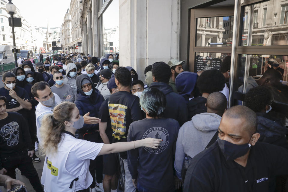 People push to enter the Niketown shop in London, Monday, June 15, 2020. After three months of being closed under coronavirus restrictions, shops selling fashion, toys and other non-essential goods are being allowed to reopen across England for the first time since the country went into lockdown in March.(AP Photo/Matt Dunham)