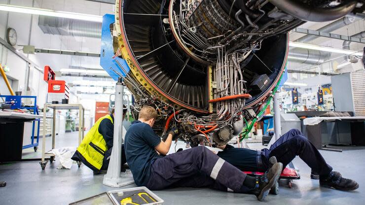 Drei Männer arbeiten in einer Werkstatt von Lufthansa Technik am Triebwerk eines Flugzeuges. Foto: dpa