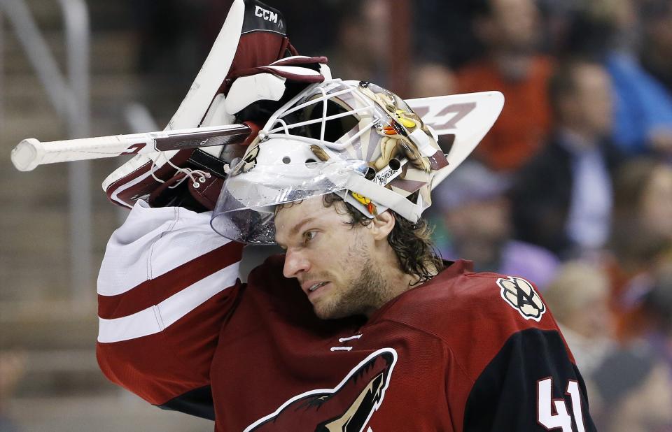 This March 22, 2016 photo shows Arizona Coyotes' Mike Smith putting his mask back on as he skates back to his position during the first period of an NHL hockey game against the Edmonton Oilers in Glendale, Ariz. When a collision knocked Smith’s mask off, the Arizona Coyotes goaltender was less than pleased when he was told a few minutes later he had no choice but to leave the game. NHL general managers expected to talk about video review and concussion protocol for goaltenders at their annual March meeting. Coach’s challenges for offside and goaltender interference will be on the docket at the GMs meeting in Boca Raton, Florida, this week. (AP Photo/Ross D. Franklin)