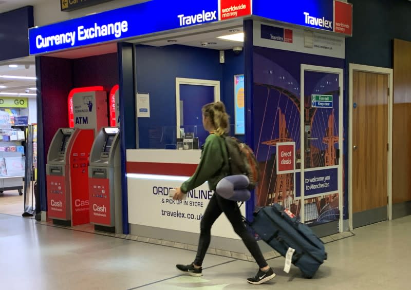 FILE PHOTO: A passenger walks past a Travelex currency exchange at Manchester Airport in Manchester, Britain