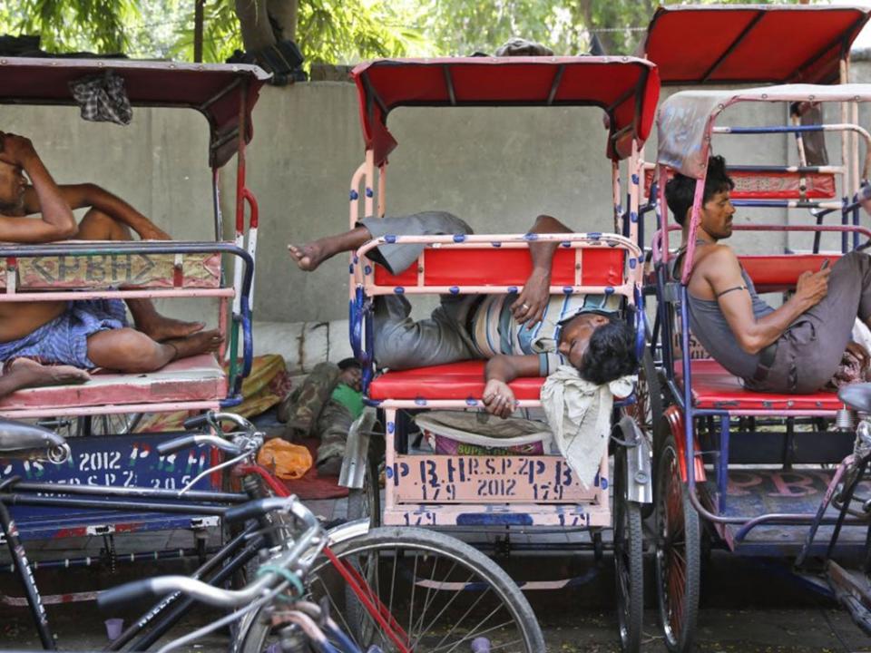 Rickshaw pullers sleep as they wait for the few customers venturing out in Delhi (PA)