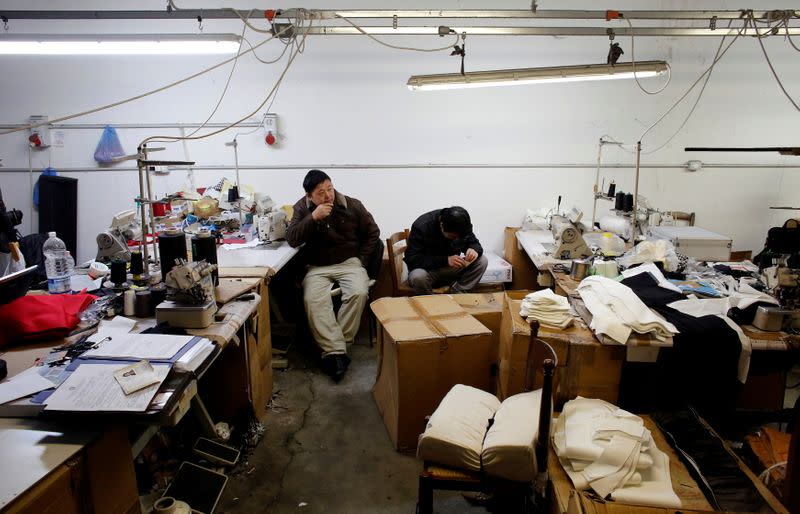 FILE PHOTO: Chinese immigrant workers watch as police officers conduct a check at a textile factory in Prato