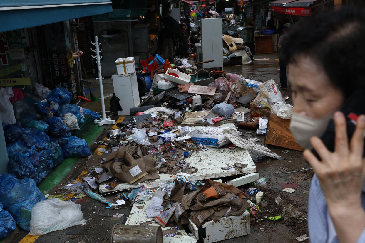 People clean up debris at a traditional market damaged by flood after torrential rain in Seoul on Tuesday. 