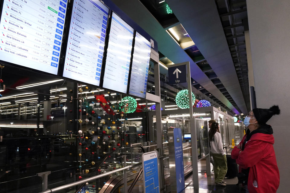 A traveler checks for her flight at the O'Hare International Airport in Chicago, Thursday, Dec. 21, 2023. It's beginning to look a lot like a hectic holiday travel season, but it might go relatively smoothly if the weather cooperates. (AP Photo/Nam Y. Huh)