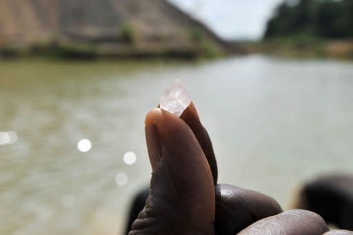 A diamond prospector shows a diamond stone as other diamond prospectors filter earth from a river in April in Koidu, the capital of the diamond-rich Kono district, in eastern Sierra Leone, some 250 km east from Freetown. Small-scale artisanal mining has sustained this area since diamonds were discovered in 1930