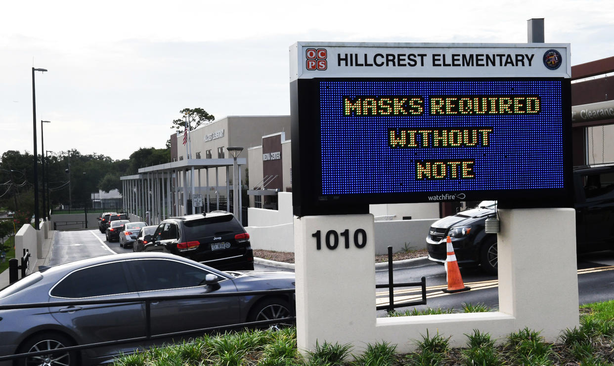Parents drop their kids off at Hillcrest Elementary school in Orlando with a sign at the entrance advising for the requirement of face masks for students unless the parents opt out of the mandate by writing a note to school officials. (Paul Hennessy/SOPA Images/LightRocket via Getty Images)