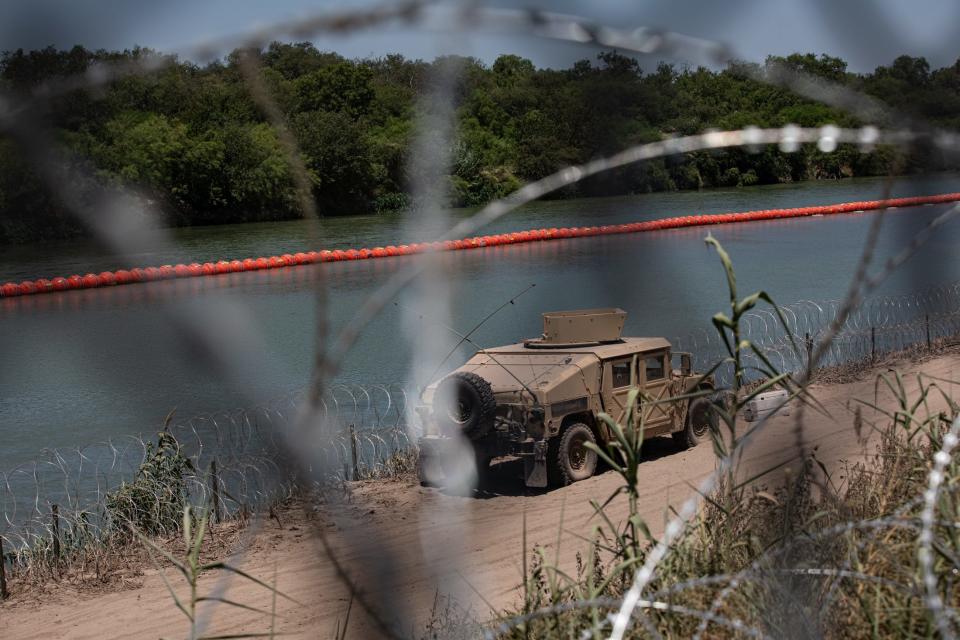 A military-style vehicle is seen parked along the Rio Grande through razor wire on Thursday, July 20, 2023, in Eagle Pass, Texas. Buoys float in the river to stop unauthorized border crossings.