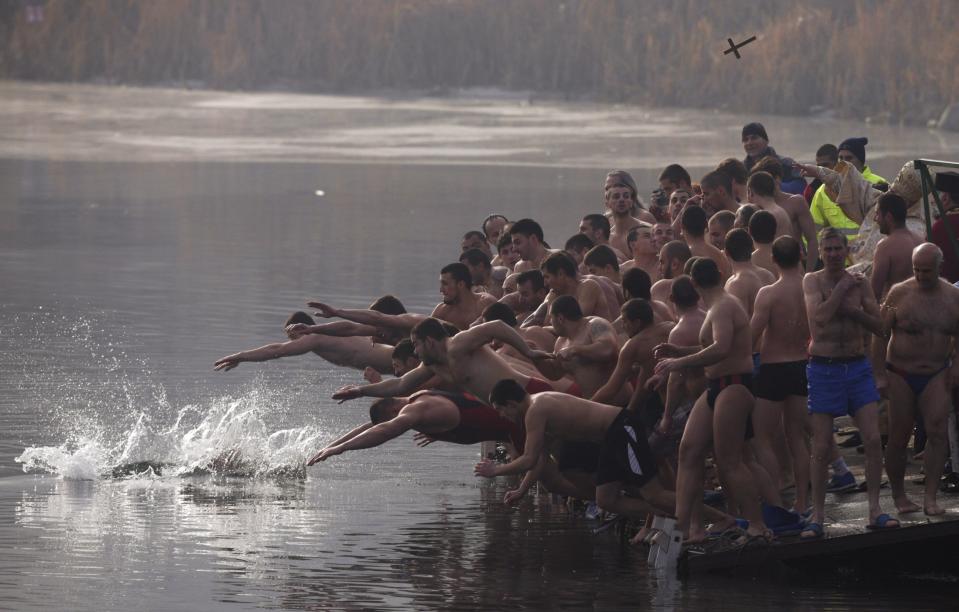 Men jump into the waters of a lake in an attempt to grab a wooden cross on Epiphany Day in Sofia January 6, 2014. Orthodox priests throughout the country bless the waters by throwing a cross into it as worshippers try to retrieve the cross. It is strongly believed that catching the cross brings health and prosperity to the person who catches it. REUTERS/Stoyan Nenov (BULGARIA - Tags: SOCIETY RELIGION TPX IMAGES OF THE DAY)