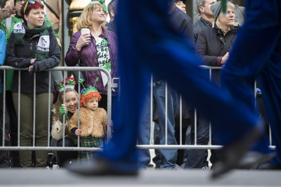 Jennifer McCaffrey, bottom left, and daughter Anastasia, 2, watch the participants march up Fifth Avenue during the St. Patrick's Day Parade, Saturday, March 16, 2019, in New York. (AP Photo/Mary Altaffer)