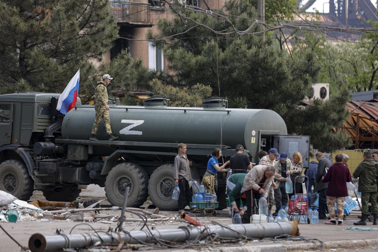 Local civilians gather to receive pure water distributed by Russian Emergency Situations Ministry in Mariupol, in territory under the government of the Donetsk People's Republic, eastern Ukraine, Friday, May 27, 2022, with the letter Z, which has become a symbol of the Russian military on a board of the truck. 