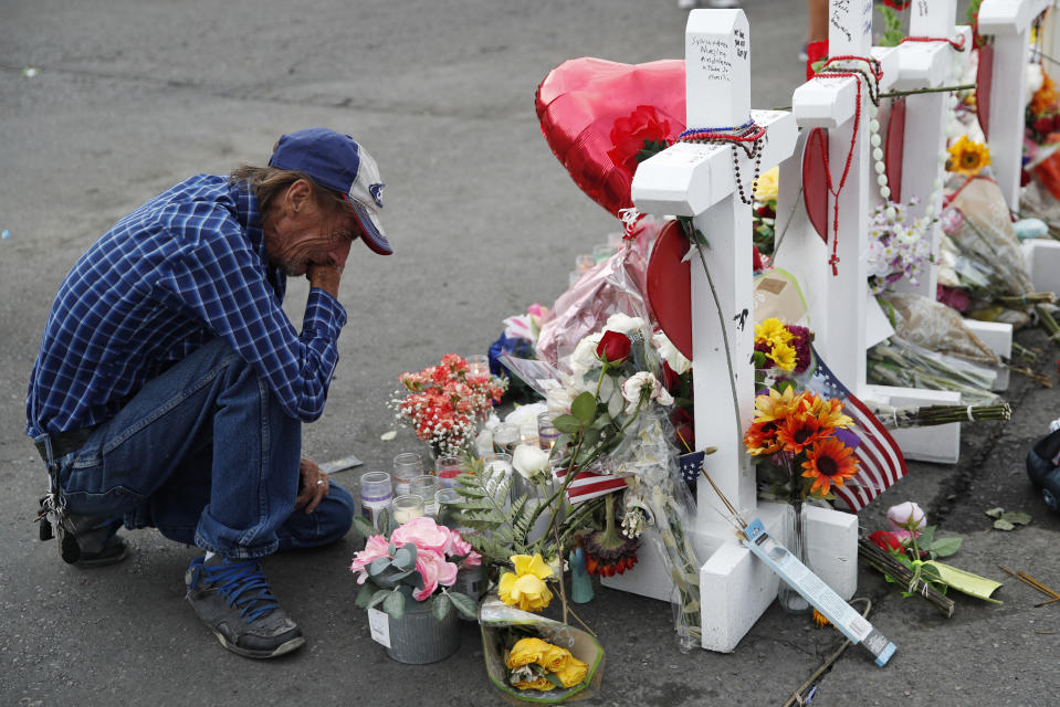 FILE - In this Aug. 6, 2019 file photo, Antonio Basco cries beside a cross at a makeshift memorial near the scene of a mass shooting at a shopping complex, in El Paso, Texas. Basco, whose 63-year-old wife was among the Texas mass shooting victims says he has no other family and welcomes anyone wanting to attend her services in El Paso. Margie Reckard was among 22 people fatally shot on Aug. 3 at a the Walmart. Reckard and Basco were married 22 years. (AP Photo/John Locher, File)