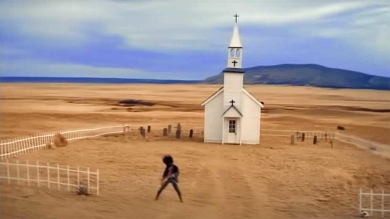  Slash plays guitar outside a chapel in the desert 