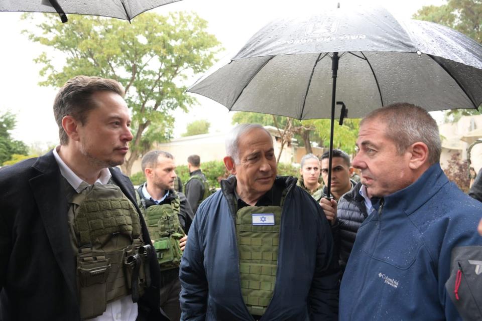 Israel's Prime Minister Benjamin Netanyahu (C) takes Elon Musk (L) on a tour of Kibbutz Kfar Aza.