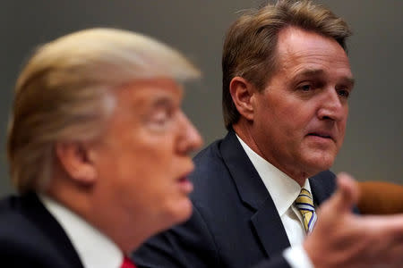 FILE PHOTO: U.S. President Donald Trump, flanked by U.S. Senator Jeff Flake, speaks to reporters prior to a lunch meeting with Senate Republicans at the White House in Washington, DC, U.S., December 5, 2017. REUTERS/Jonathan Ernst/File Photo