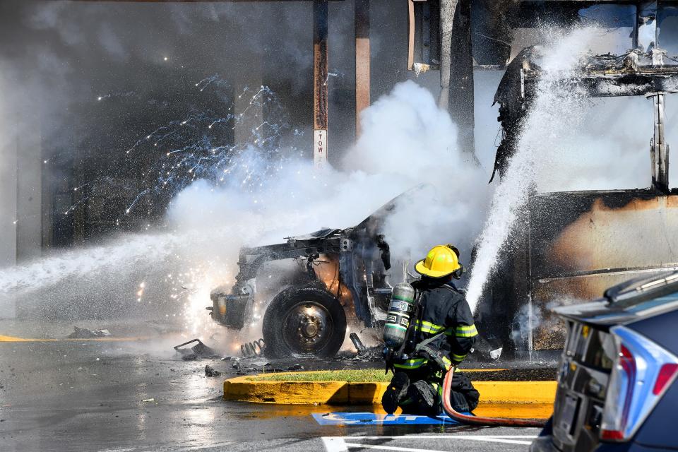 Sparks shoot out of the engine compartment as firefighters extinguish a burning vehicle at Madison Place shopping center Saturday.