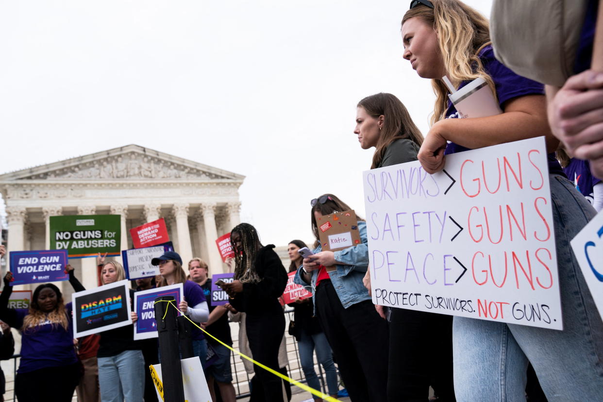 Demonstrators outside Supreme Court building hold signs, one of which reads: Survivors over guns, safety over guns, peace over guns. Protect survivors, not guns.