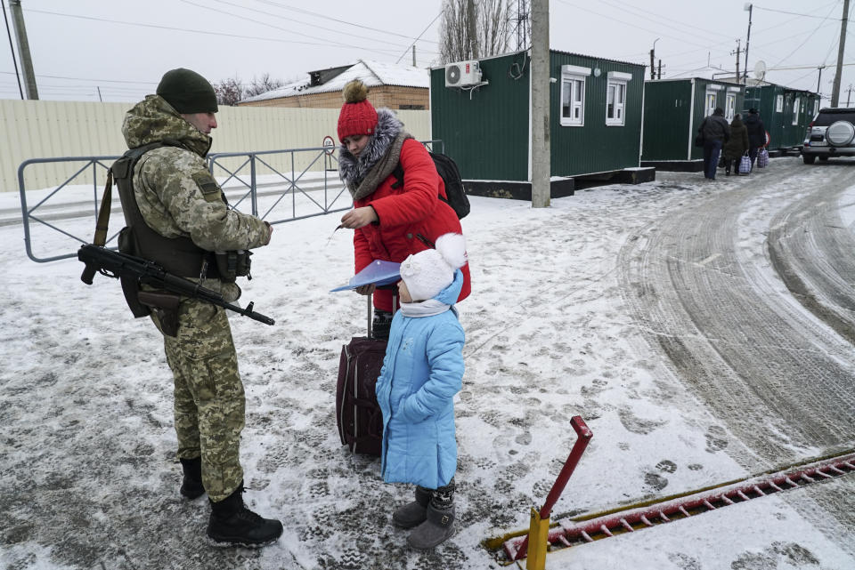 A Ukrainian border guard checks documents of a woman crossing the border the Ukraine - Russia border in Milove town, eastern Ukraine, Sunday, Dec. 2, 2018. On a map, Chertkovo and Milove are one village, crossed by Friendship of Peoples Street which got its name under the Soviet Union and on the streets in both places, people speak a mix of Russian and Ukrainian without turning choice of language into a political statement. (AP Photo/Evgeniy Maloletka)