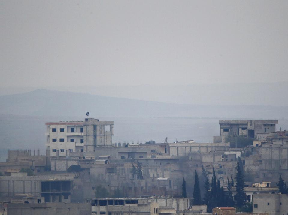 A black flag belonging to the Islamic State is seen on top of a house in the Syrian town of Kobani, pictured from near the Mursitpinar border crossing on the Turkish-Syrian border in the southeastern town of Suruc in Sanliurfa province, October 17, 2014. Two days of heavy air strikes by U.S. warplanes have slowed an advance by Islamic State militants against Kurdish forces defending the Syrian border town of Kobani. REUTERS/Kai Pfaffenbach (TURKEY - Tags: MILITARY CONFLICT POLITICS)