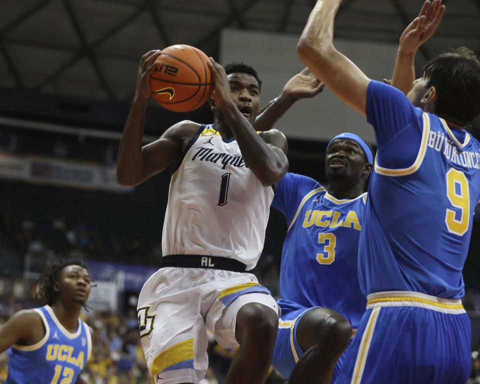 Marquette guard Kam Jones (1) goes to the net between UCLA forward Adem Bona (3) and forward Berke Buyuktuncel (9) during the first half of an NCAA college basketball game, Monday, Nov. 20, 2023, in Honolulu. (AP Photo/Marco Garcia)