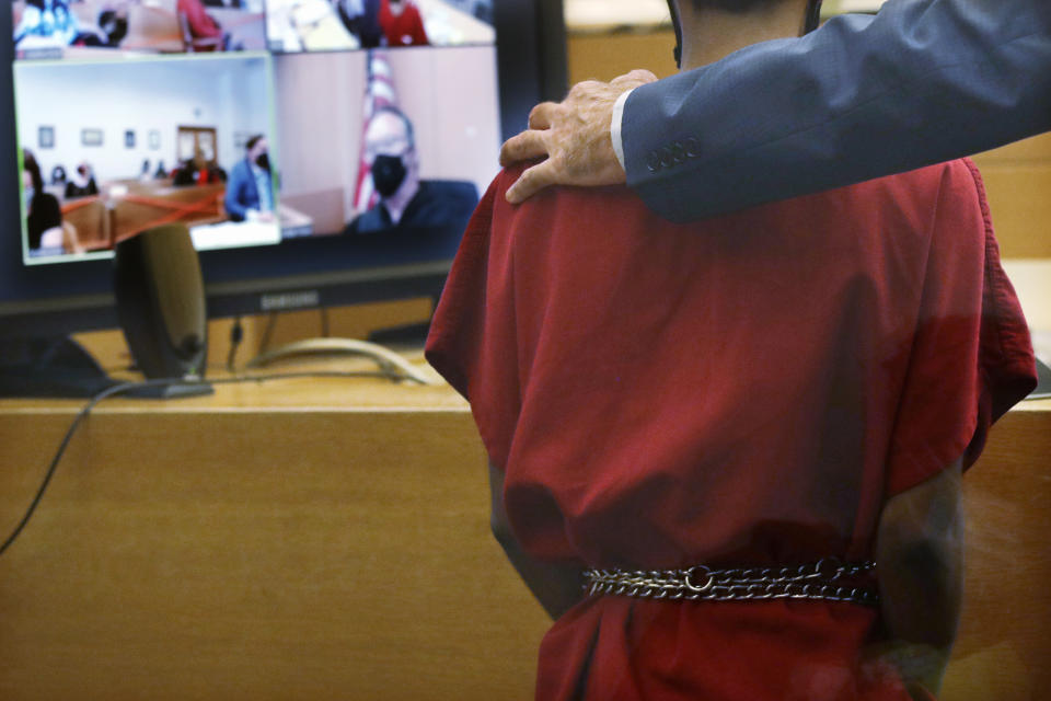 Attorney John Henry Browne puts his arm over the shoulders of Dawit Kelete as Kelete makes a court appearance before Judge Mark Chow, on video, Monday, July 6, 2020, in Seattle. Kelete is accused of driving a car onto a closed Seattle freeway and hitting two protesters, killing one, over the weekend. Seattle has been the site of prolonged unrest over the death of George Floyd, a Black man who was in police custody in Minneapolis. (AP Photo/Elaine Thompson)