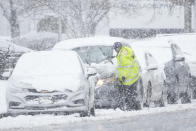 A person cleans off a car during a winter snow storm in Philadelphia, Tuesday, Feb. 13, 2024. (AP Photo/Matt Rourke)