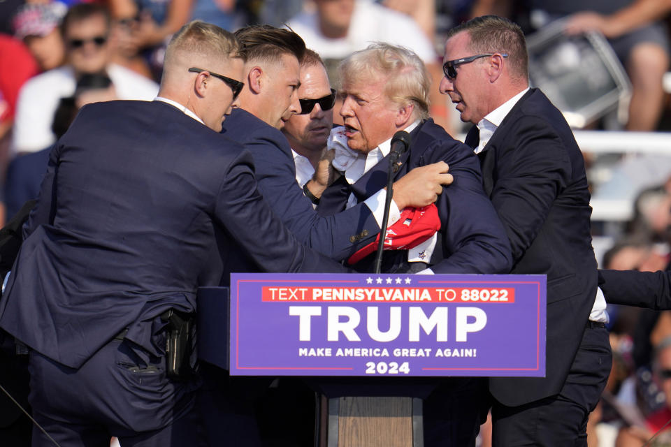 Republican presidential candidate former President Donald Trump is helped off the stage at a campaign event in Butler, Pa., on Saturday, July 13, 2024. (AP Photo/Gene J. Puskar)
